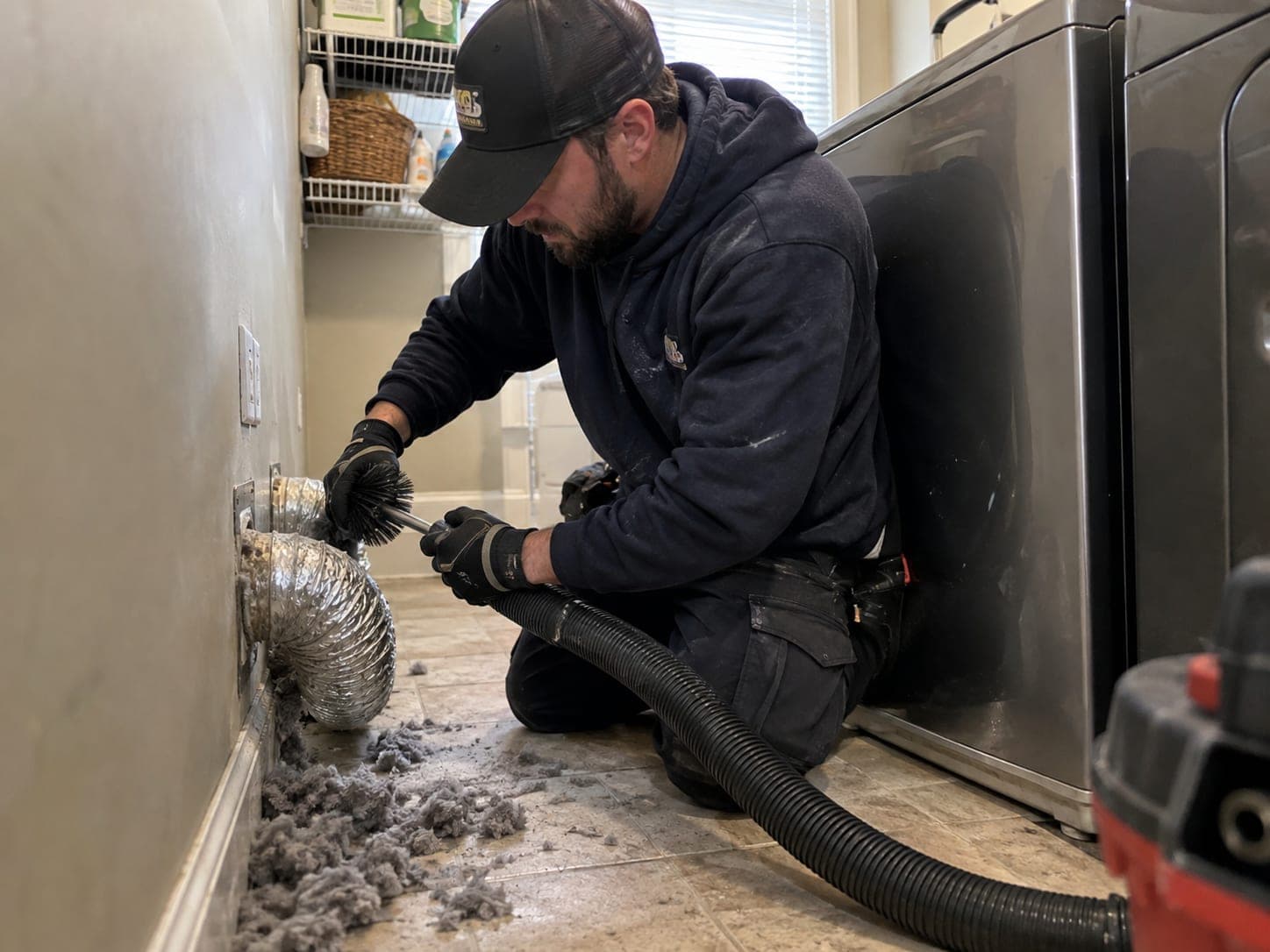 Technician brushing a dryer duct indoors